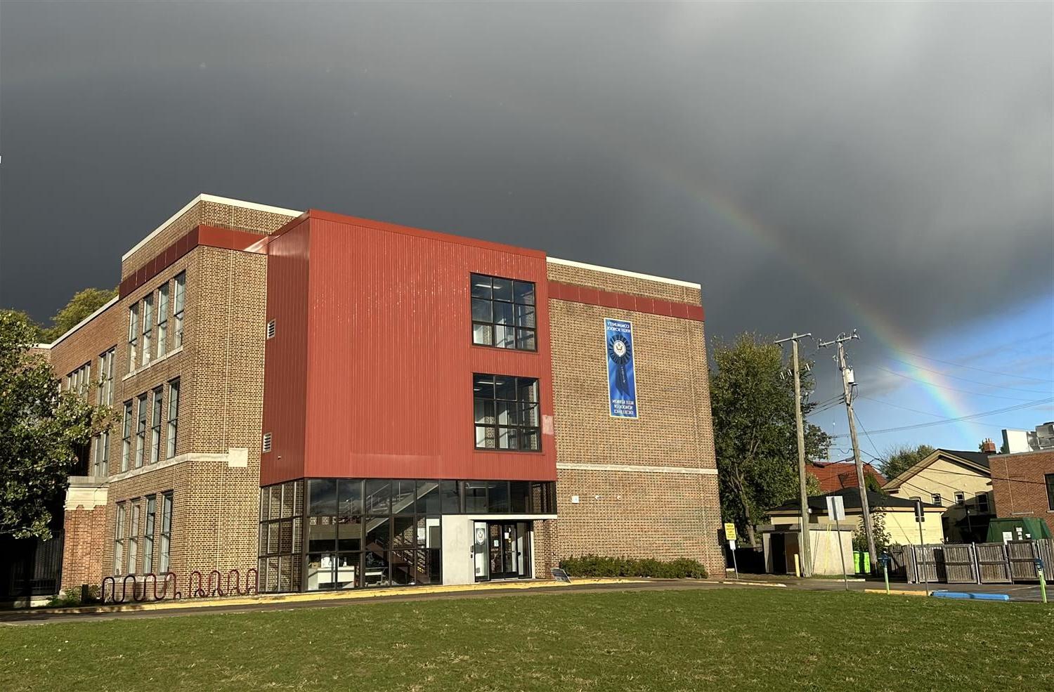 Rainbow in sky over community high school building